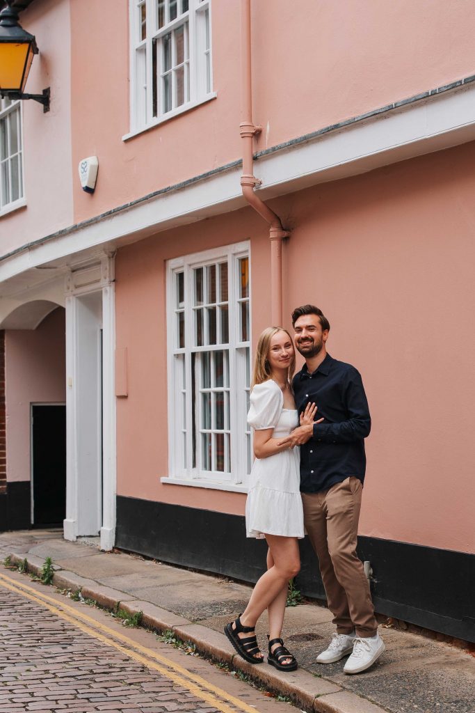 Sarah and James pictured in front of a pink house